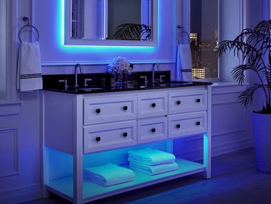 A vanity and mirror with blue light shining out from underneath both.